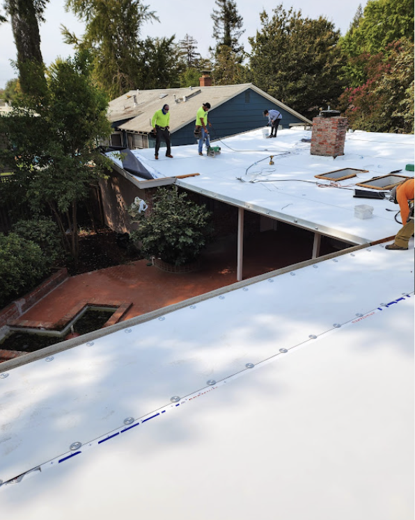 Crew installing white flat roof membrane